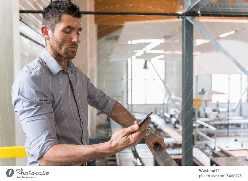 Businessman using cell phone in factory factories mobile phone mobiles mobile phones Cellphone cell phones Business man Businessmen Business men telephones