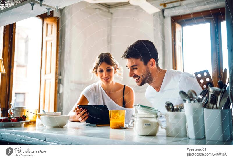 Young couple watching tablet while having breakfast at home human human being human beings humans person persons caucasian appearance caucasian ethnicity