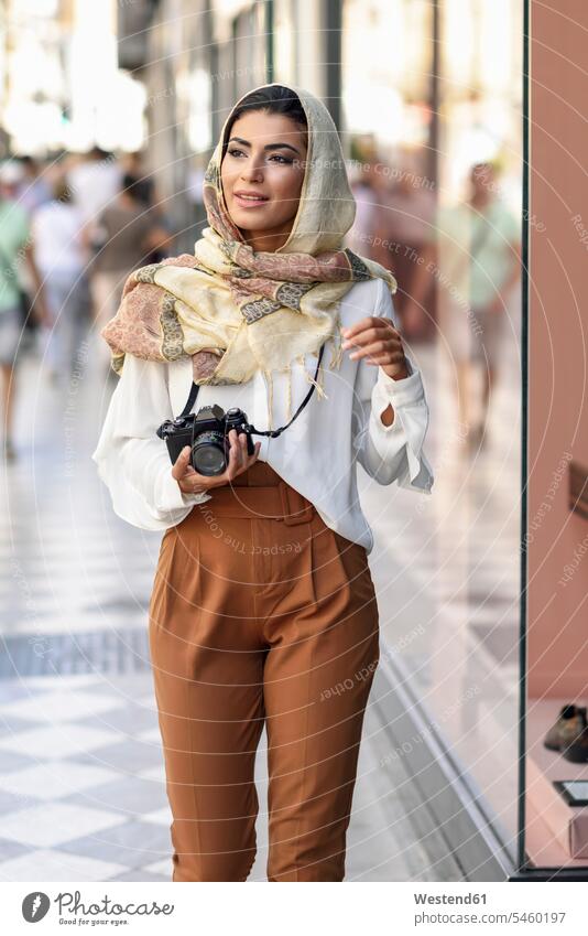 Spain, Granada, young Arab tourist woman wearing hijab, using fotocamera during shopping in the city headscarf head scarf head scarves Head Scarf head cloths