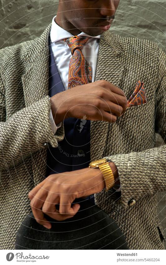 Stylish businessman holding a beret and checking his pocket square human human being human beings humans person persons African black black ethnicity coloured 1