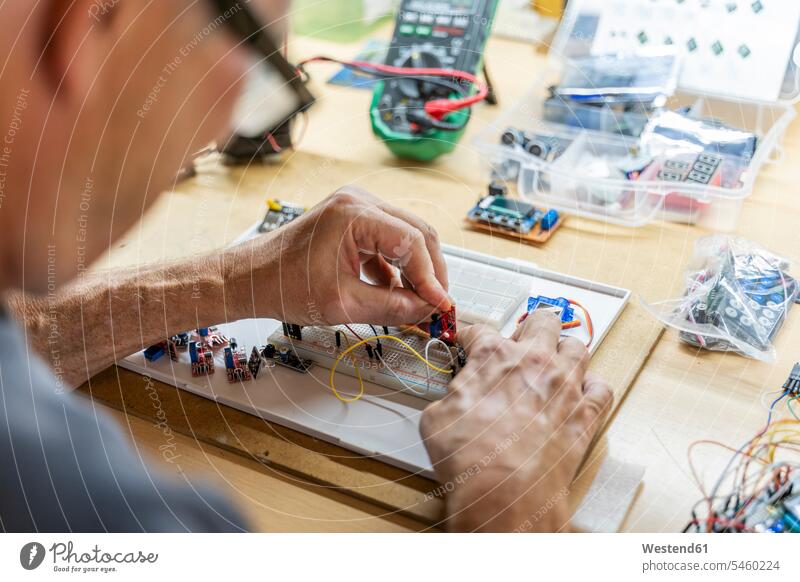 Senior man working on electronic circuits in his workshop Occupation Work job jobs profession professional occupation cables power cord computers At Work repair