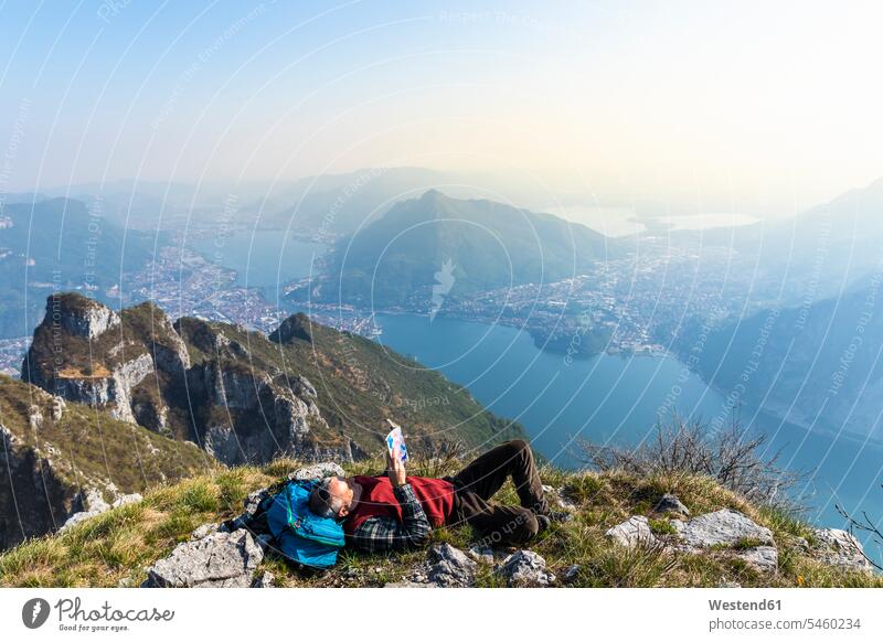 Rear view of hiker reading a book on mountaintop, Orobie Alps, Lecco, Italy Landscape - Nature Landscape - Scenery landscapes scenery terrain Alpine Landscape
