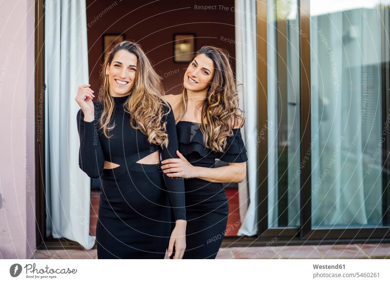 Smiling twin sisters wearing dresses standing outdoors at tourist resort color image colour image Spain leisure activity leisure activities free time
