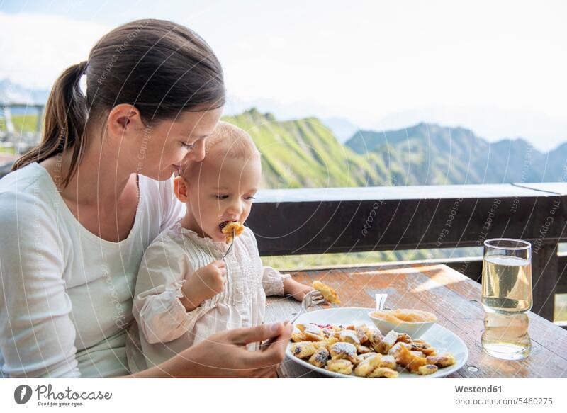 Germany, Bavaria, Oberstdorf, mother and little daughter having lunch at a mountain hut mommy mothers mummy mama mountain shelter alpine hut mountain huts