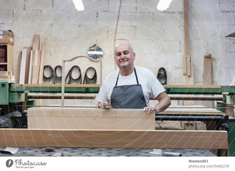 Smiling mature man holding plank while standing at workshop color image colour image indoors indoor shot indoor shots interior interior view Interiors workplace
