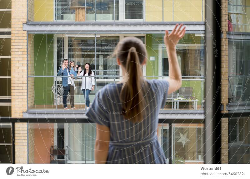 Back view of woman standing on balcony waving to her neighbours windows wave Waving - Gesture free time leisure time Lifestyle location shot location shots