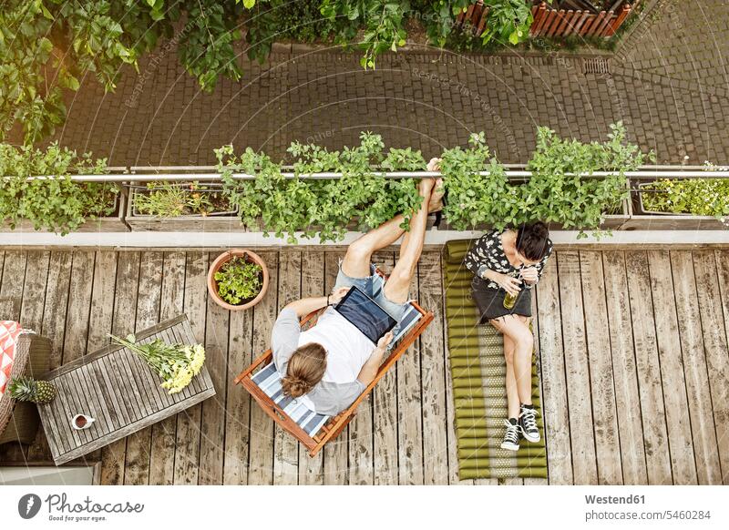 Young couple relaxing on their balcony in summer, man using tablet Plant Plants digitizer Tablet Computer Tablet PC Tablet Computers iPad Digital Tablet