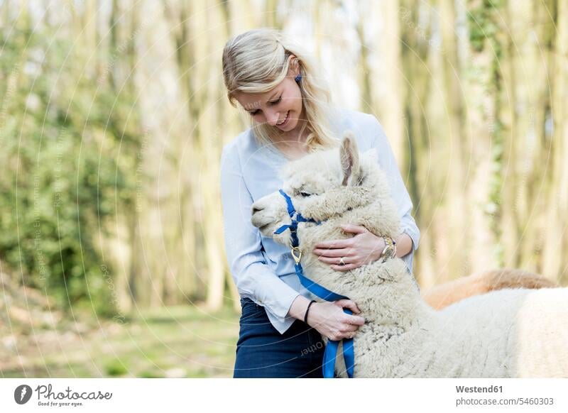 Happy woman cuddling alpaca Germany nature natural world hugging animal themes leash leashes bridle bridles confidence confident familiarity copy space