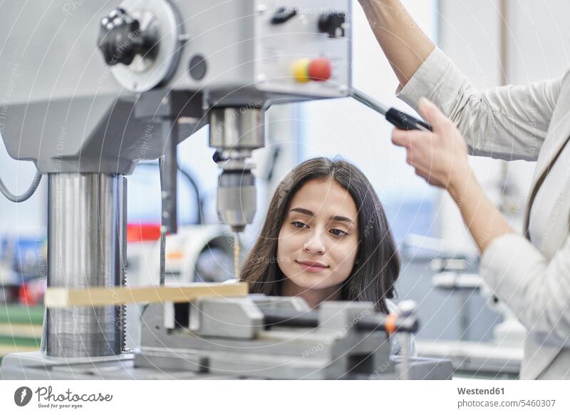 Cropped image of manager drilling metal while training female worker in metal industry color image colour image indoors indoor shot indoor shots interior