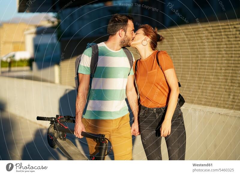 Kissing couple with folded electric scooter human human being human beings humans person persons caucasian appearance caucasian ethnicity european 2 2 people