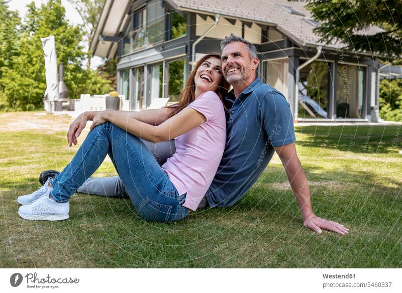 Happy couple sitting in garden of their home Seated gardens domestic garden house houses twosomes partnership couples happiness happy building buildings