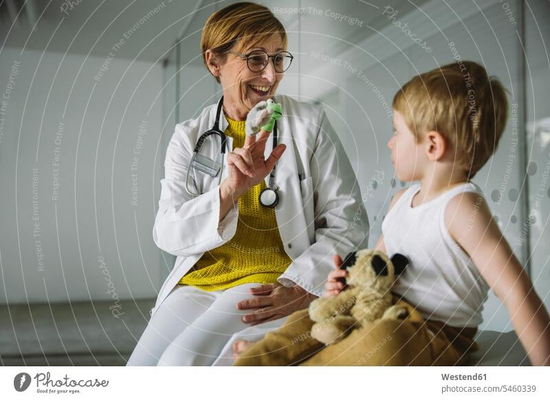 Peditrician with finger dolls and toddler in medical practice human human being human beings humans person persons caucasian appearance caucasian ethnicity