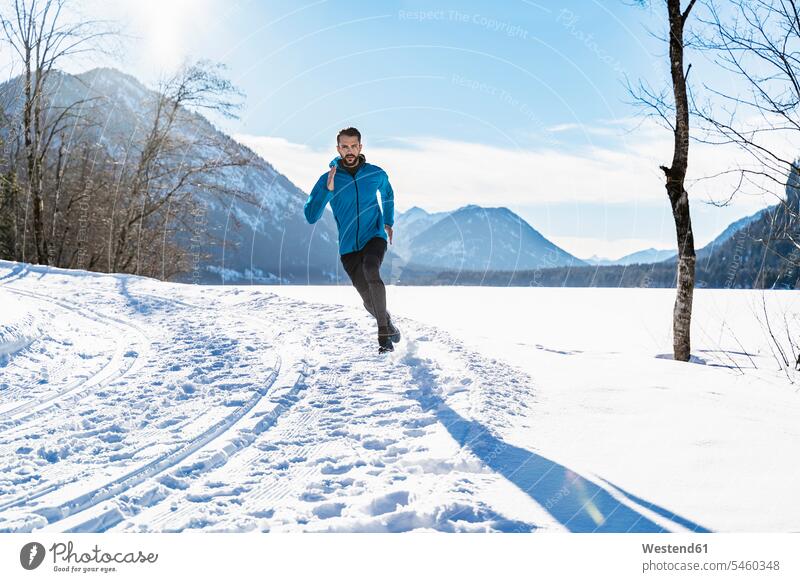 Germany, Bavaria, sportive man running through snow in winter men males hibernal sporting sporty athletic Adults grown-ups grownups adult people persons
