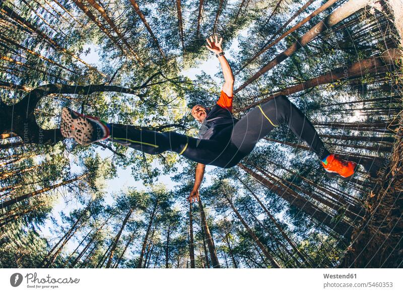 Mature man jumping against trees in forest color image colour image Spain outdoors location shots outdoor shot outdoor shots day daylight shot daylight shots