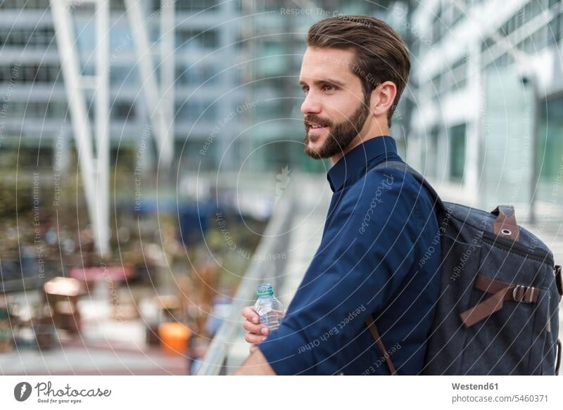 Smiling young businessman with backpack and bottle of water outdoors water bottle water bottles bottled water Businessman Business man Businessmen Business men