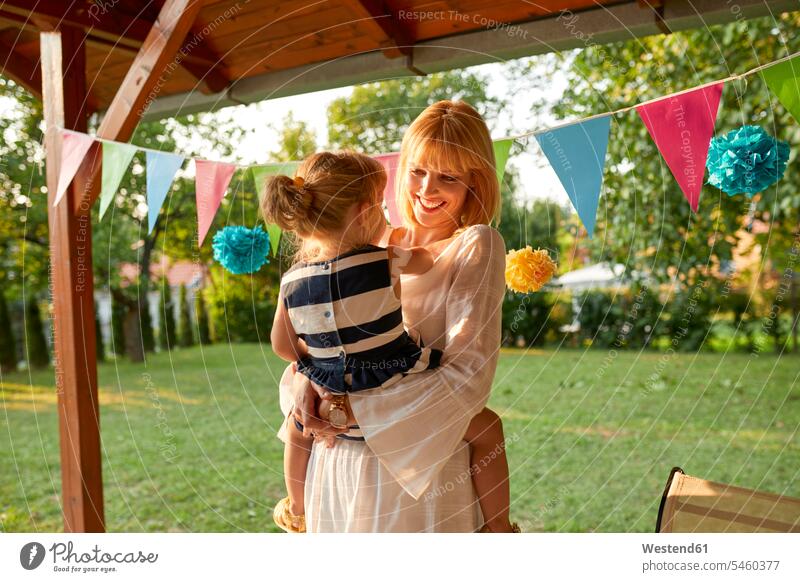Happy mother carrying her daughter on a garden birthday party Celebration Celebrations Celebration Event Ceremonies Festivity Ceremony Festivities daughters