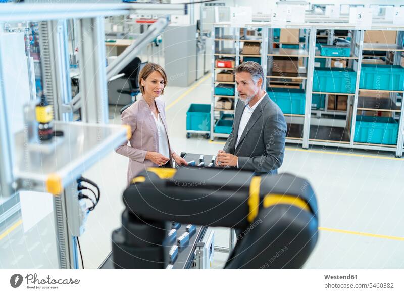 Businessman and businesswoman talking in a modern factory hall human human being human beings humans person persons caucasian appearance caucasian ethnicity