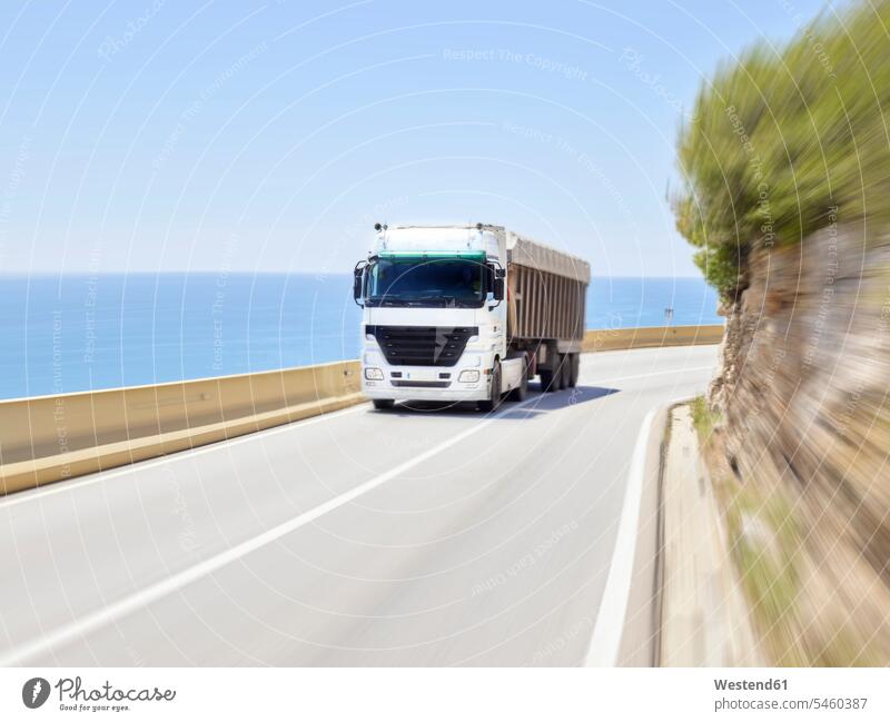 Truck driving along Jersey barrier of coastal highway, Sitges, Barcelona, Spain outdoors location shots outdoor shot outdoor shots day daylight shot