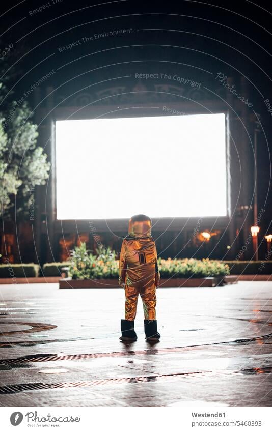 Spaceman on a square at night attracted by shining projection screen astronaut astronauts Projection Screen plaza places Public Square city town cities towns