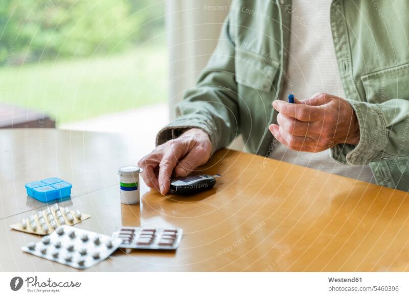 Midsection of retired diabetic senior man examining himself while sitting at table color image colour image indoors indoor shot indoor shots interior