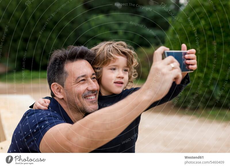 Happy father and son on taking a selfie in park happiness happy parks Selfie Selfies fathers daddy dads papa sons manchild manchildren parents family families
