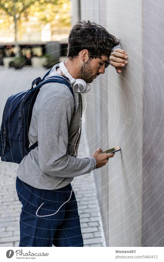 Man leaning against a wall checking cell phone human human being human beings humans person persons caucasian appearance caucasian ethnicity european 1