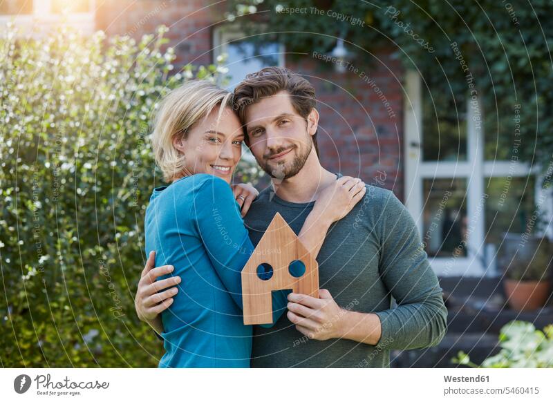 Portrait of happy couple in front of their home with house model models portrait portraits houses twosomes partnership couples happiness people persons