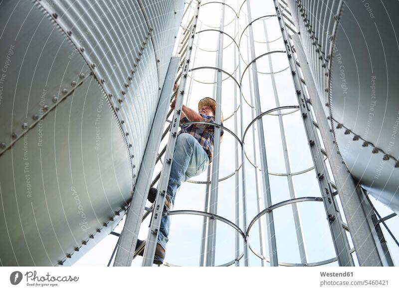 Farmer climbing up ladder at tank Storage Tanks tanks storage tank farmer agriculturists farmers ladders agriculture copy space skill Ability skilled Competence