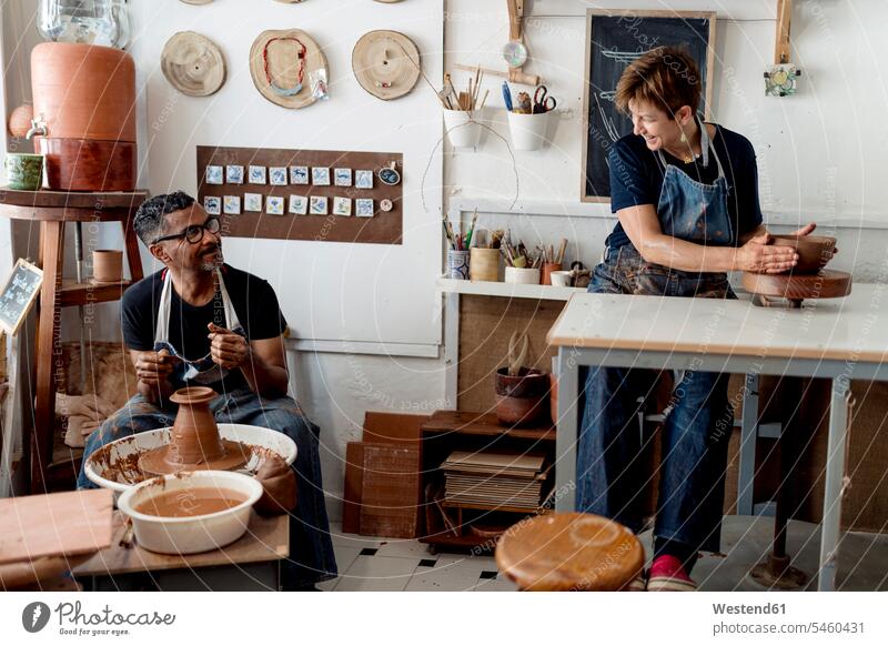 Coworkers talking while making pottery in workshop color image colour image Spain indoors indoor shot indoor shots interior interior view Interiors working