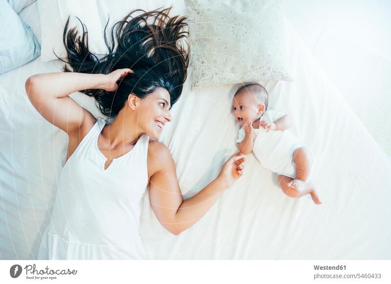 Smiling mother lying in bed with her baby boy human human being human beings humans person persons caucasian appearance caucasian ethnicity european 2 2 people