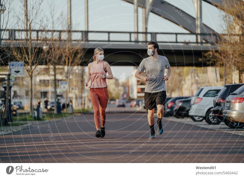 Young couple jogging on road in city during coronavirus color image colour image outdoors location shots outdoor shot outdoor shots day daylight shot