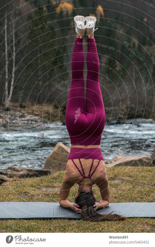 Active young woman practicing headstand pose on yoga mat at Ordesa National Park, Huesca, Spain color image colour image outdoors location shots outdoor shot