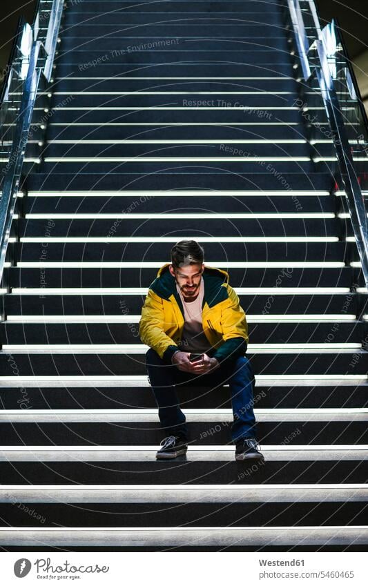Man sitting on stairs in subway station using cell phone human human being human beings humans person persons caucasian appearance caucasian ethnicity european