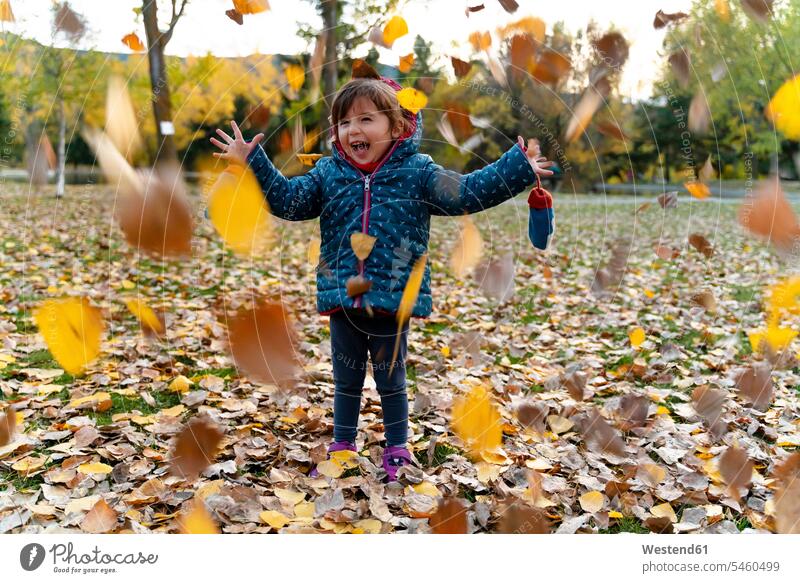 Little girl playing with autumn leaves outdoors coat coats jackets fall smile Ardor Ardour enthusiasm enthusiastic excited delight enjoyment Pleasant pleasure