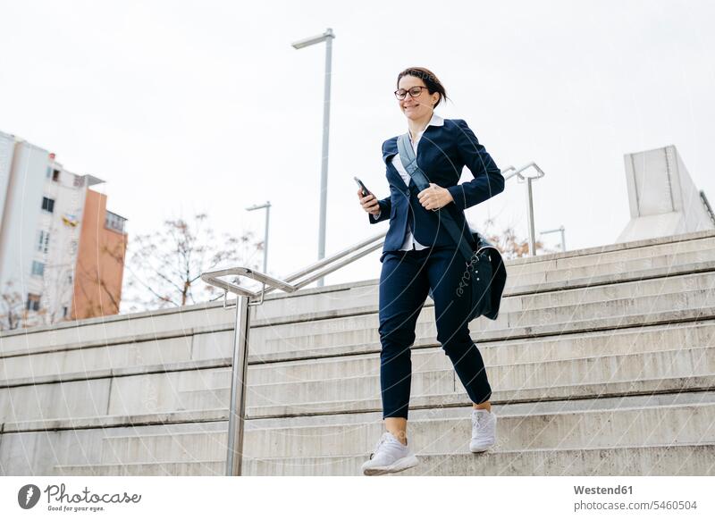 Active businesswoman moving downstairs in the city stairway businesswomen business woman business women move town cities towns downwards business people