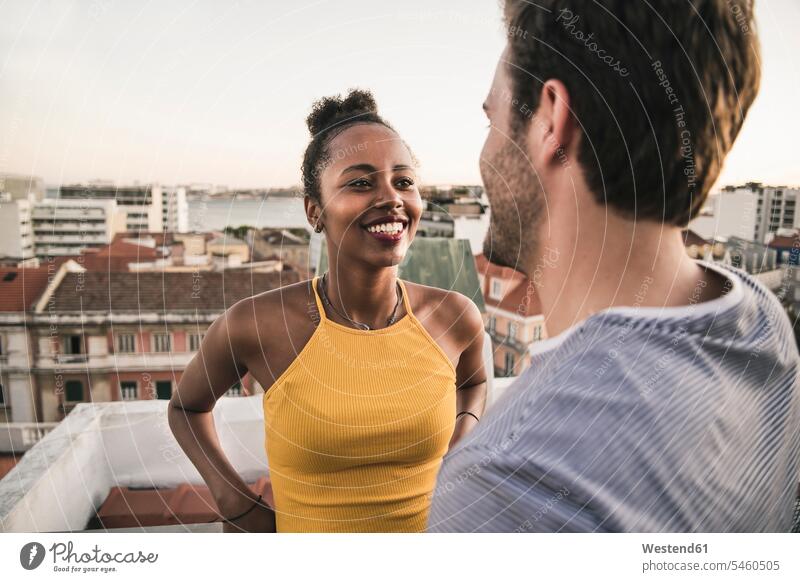 Happy young couple talking on rooftop in the evening human human being human beings humans person persons African black black ethnicity coloured
