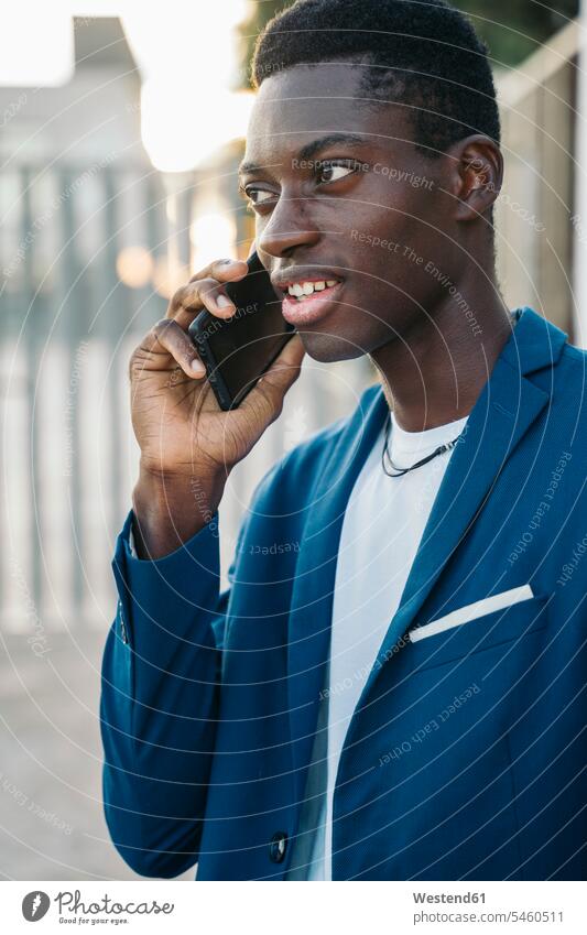 Young businessman in blazer talking on mobile phone call outdoors color image colour image location shots outdoor shot outdoor shots day daylight shot