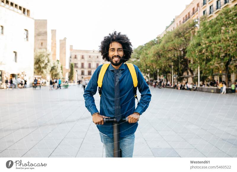 Portrait of smiling man with backpack on his E-Scooter after work, Barcelona, Spain back-pack back-packs backpacks rucksack rucksacks business attire