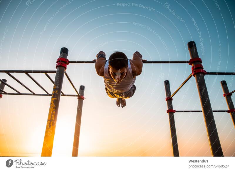 Young man practicing calisthenics at an outdoor gym at sunrise human human being human beings humans person persons caucasian appearance caucasian ethnicity