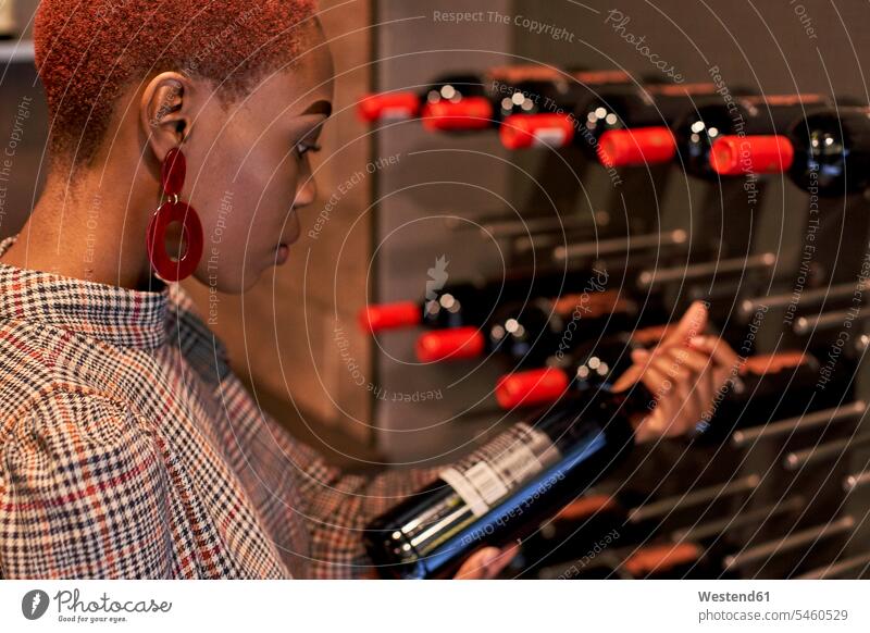 Young woman with short haircut choosing a wine in her cellar human human being human beings humans person persons African black black ethnicity coloured 1