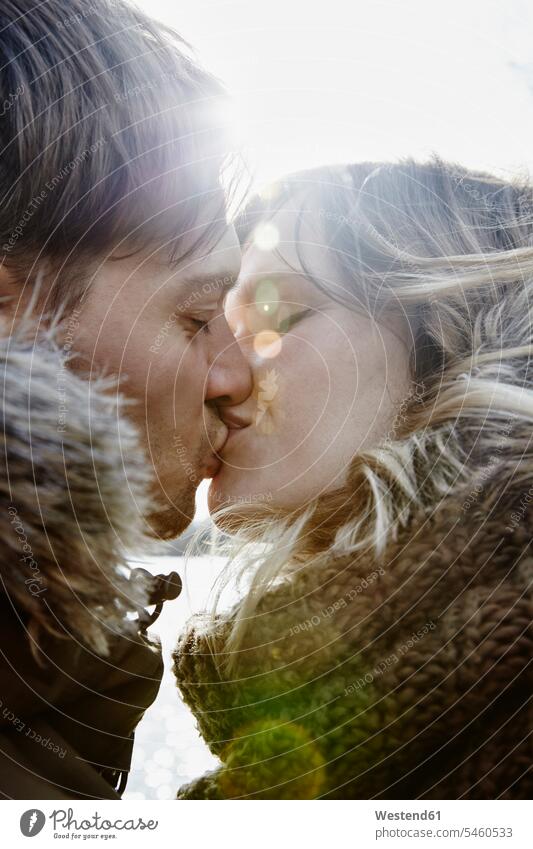 Kissing young couple in winter at backlight kiss kisses in the evening Late Evening seasons hibernal happy Emotions Feeling Feelings Sentiment Sentiments loving