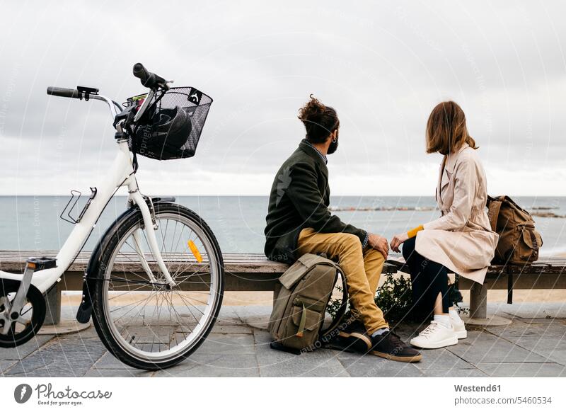 Couple sitting on a bench at beach promenade next to e-bike looking at the sea E-Bike Electric bicycle Electric Bike break ocean couple twosomes partnership