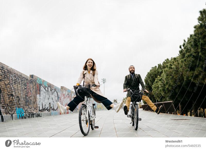 Carefree couple riding e-bikes on a promenade promenades bicycle bicycles E-Bike Electric bicycle Electric Bike twosomes partnership couples carefree