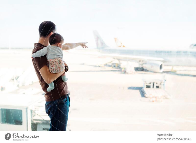 Spain, Barcelona, Man holding a baby girl at the airport pointing at the airplanes terminal airports Looking Through Window Looking Through A Window