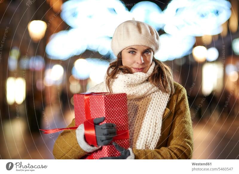 Portrait of smiling woman with Christmas present in the evening females women portrait portraits Christmas presents smile Adults grown-ups grownups adult people