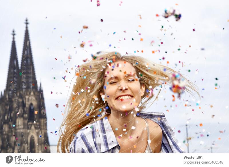 Germany, Cologne, portrait of happy blond woman in between shower of confetti blond hair blonde hair portraits females women happiness people persons