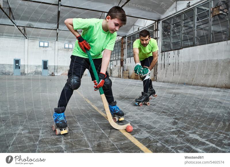 Boy practicing roller hockey with father on court color image colour image Spain indoors indoor shot indoor shots interior interior view Interiors 10-11 years