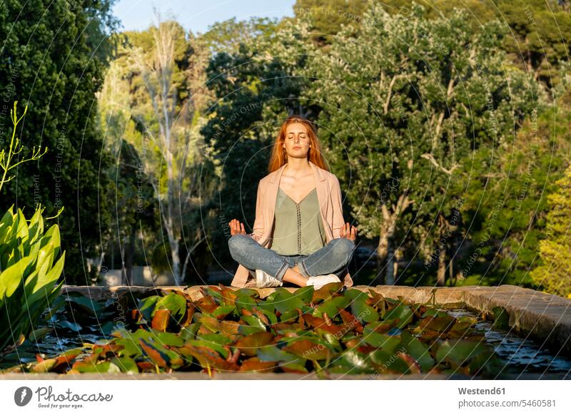 Young redheaded woman meditating in a park human human being human beings humans person persons caucasian appearance caucasian ethnicity european adult grown-up