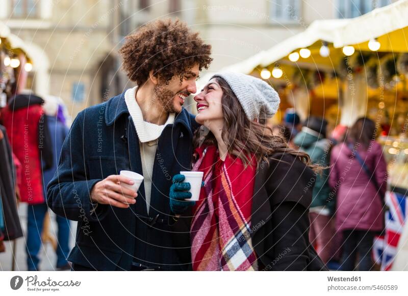 Happy affectionate young couple with hot drinks at Christmas market Affection Affectionate hot beverage hot beverages happiness happy twosomes partnership