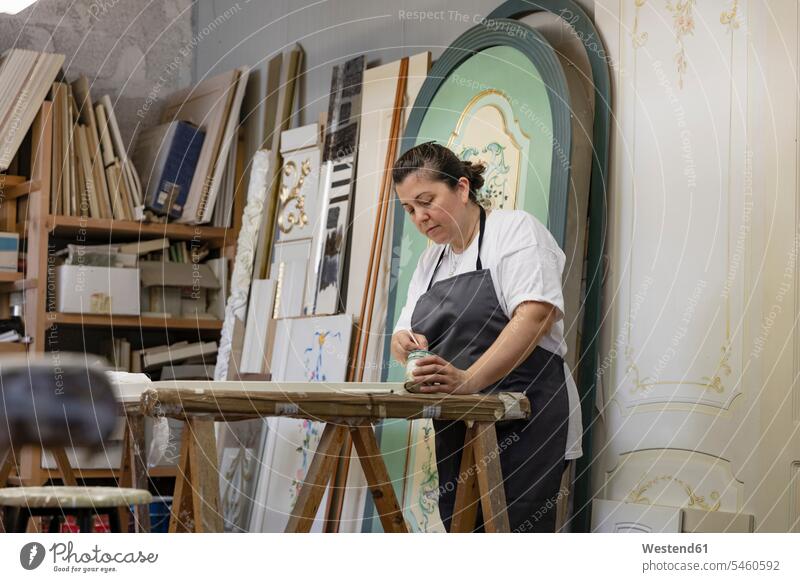 Mature woman painting door while standing at art studio color image colour image indoors indoor shot indoor shots interior interior view Interiors workplace